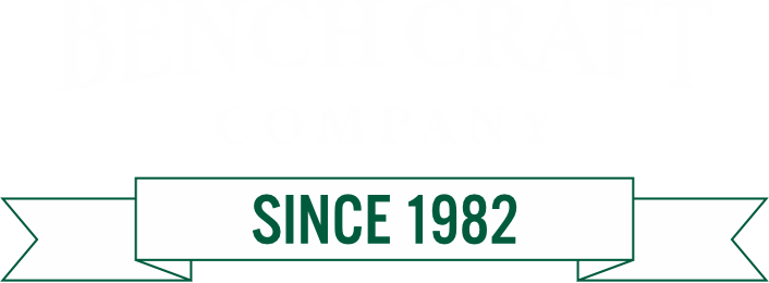 Faint Benchcraft Company wordmark above a green ribbon banner reading SINCE 1982.